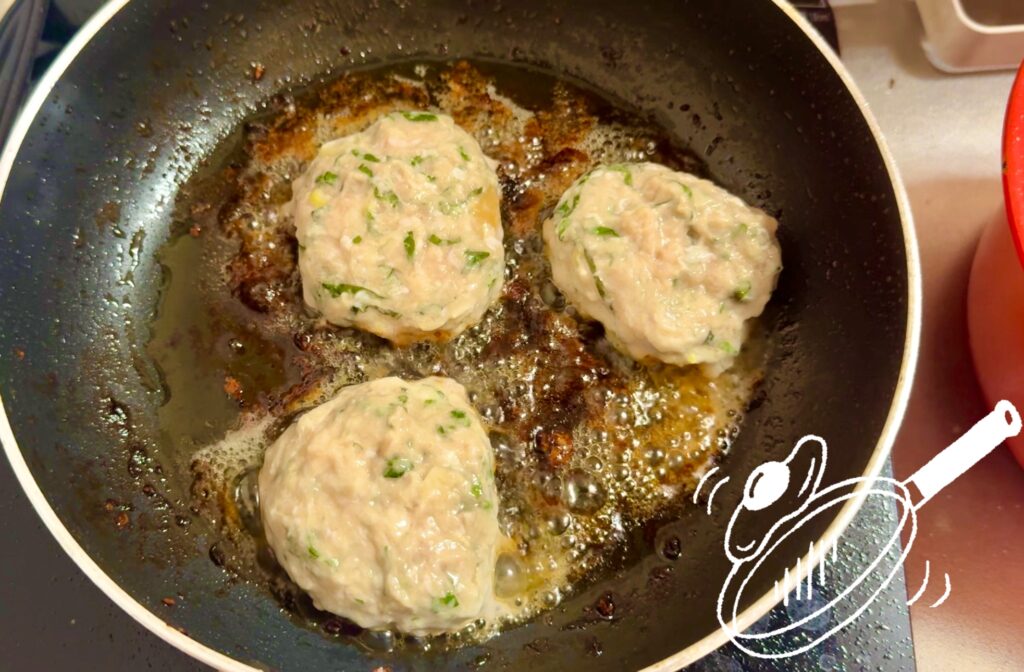 油を熱したフライパンで鶏つくねを焼く