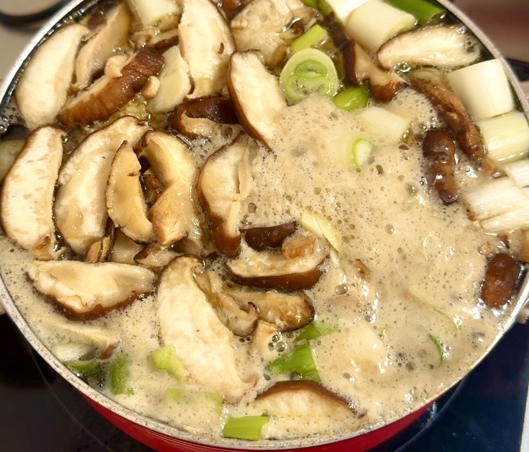骨付き鶏もも肉を煮込みながら灰汁を取る参鶏湯風スープ